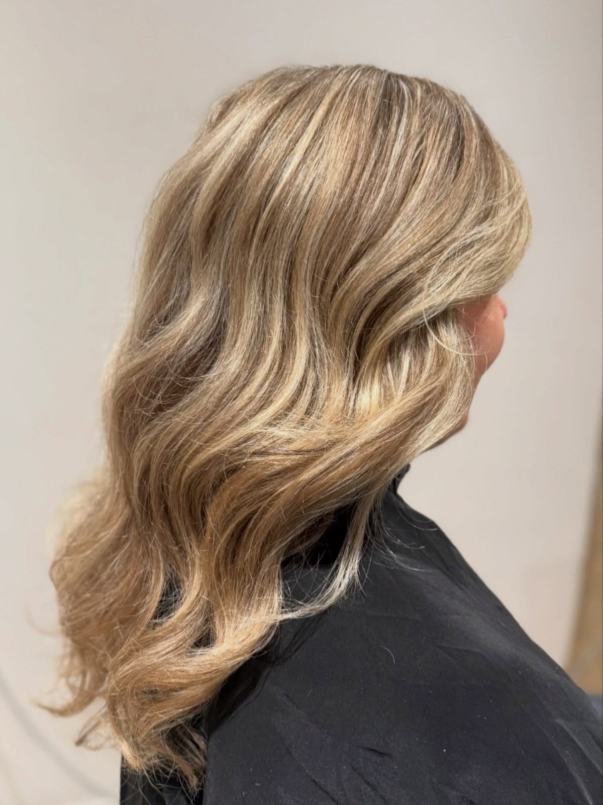 Lang golvend blond haar met warme lokken, van opzij gezien in de salon