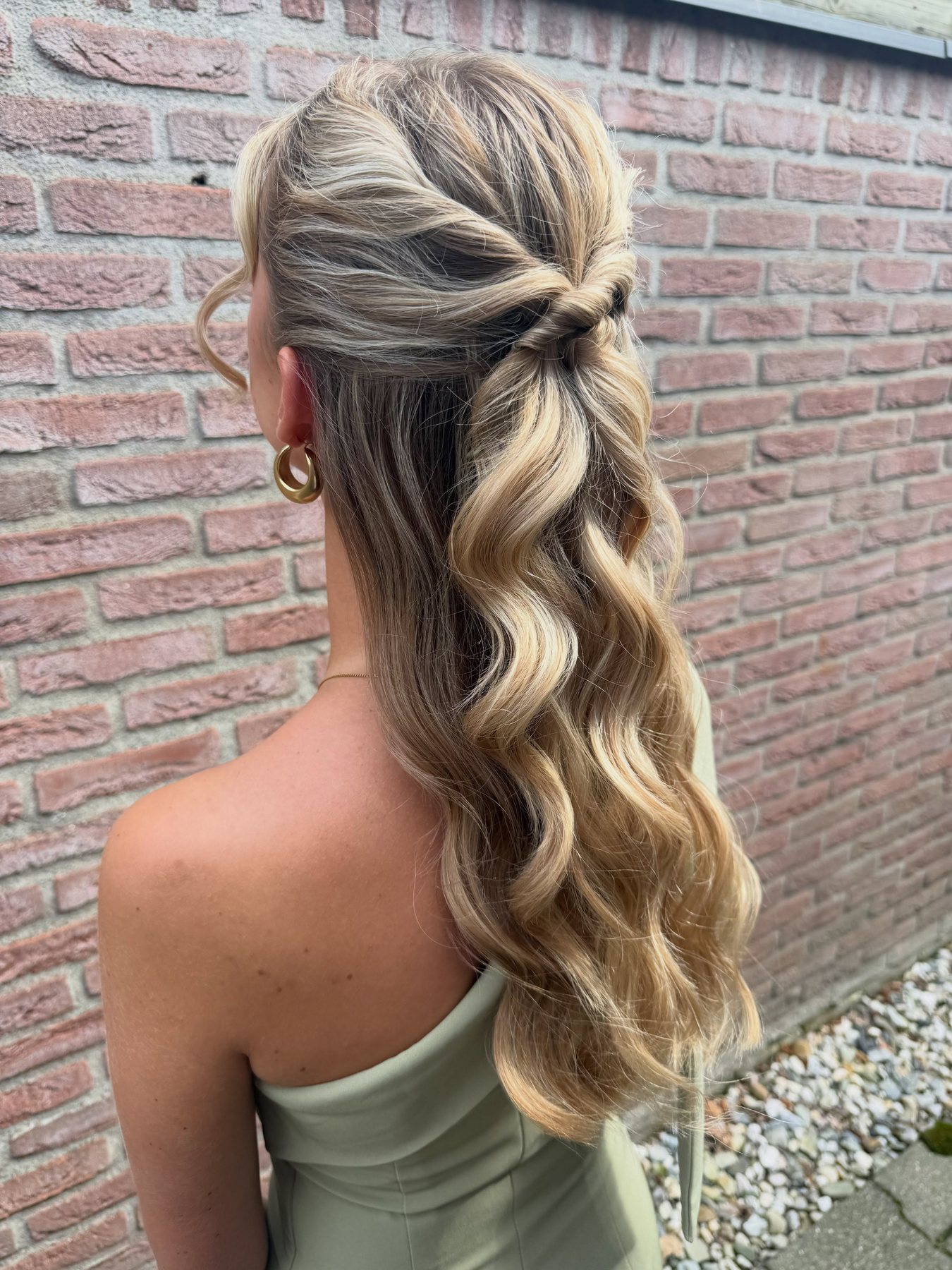 Half opgestoken kapsel met grote golven in blond haar, van achteren gezien